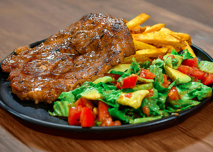 Grilled steak with fries and a fresh salad, challenging stereotypes about the US.
