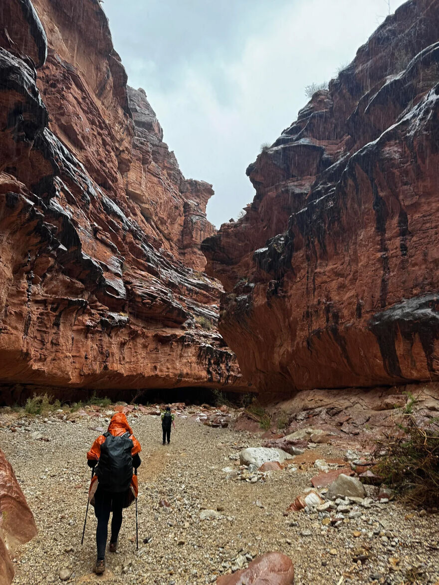 Two hikers trek through a narrow canyon in the rain, exploring the most isolated places on Earth.