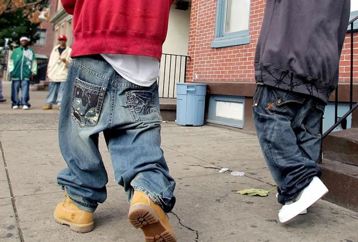 Street scene showing people wearing baggy jeans walking on sidewalk