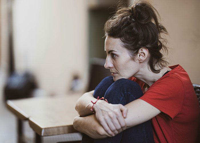 Pensive woman sitting with knees hugged, reflecting mysterious vanished people