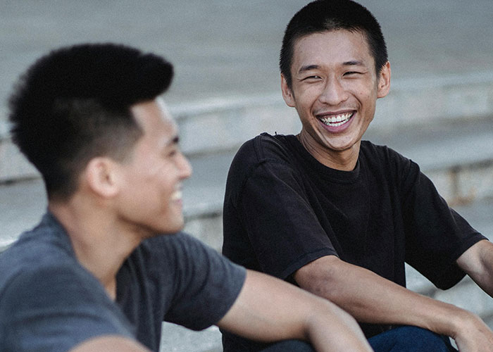 Two young men smiling outdoors, debunking US stereotypes.