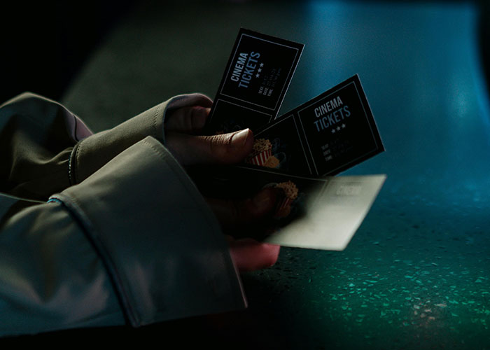 Hands holding cinema tickets, a representation of spending, reflecting people worry about the economy and their wallets.