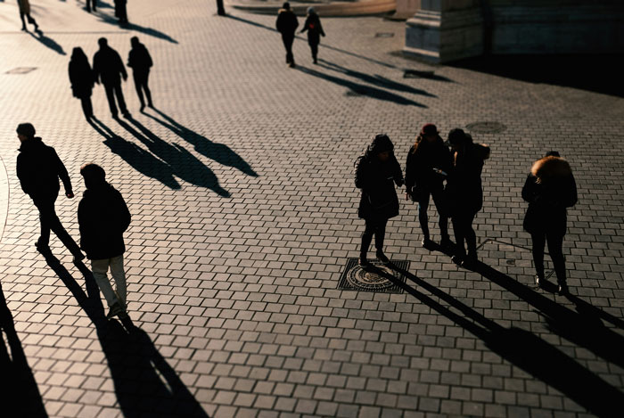 Shadows of people on tiled pavement creating glitch in the matrix visual effect