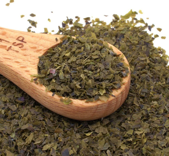 Dried artisinal herbs in wooden teaspoon closeup