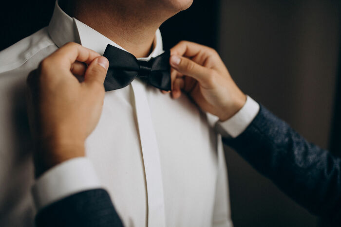 Man adjusting groom's bow tie for wedding