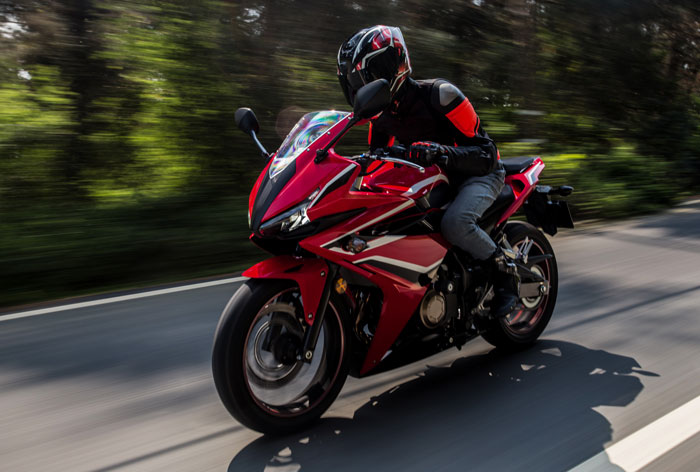 Motorcyclist in black and red gear riding red sport bike fast