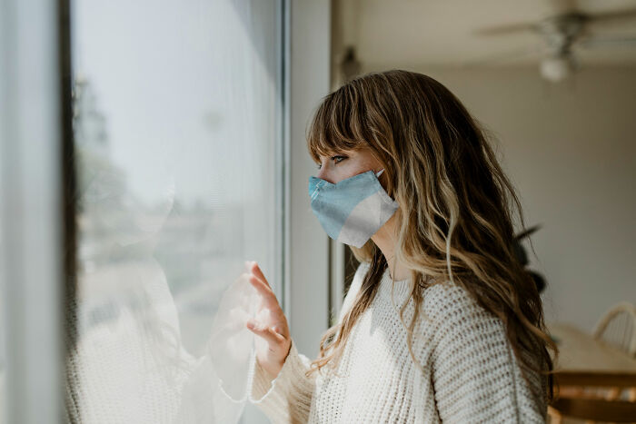 Woman wearing face mask looking out window during January 6 times