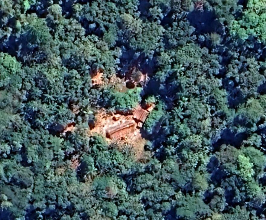 Aerial view of an isolated village clearing within a dense forest, showcasing one of Earth's most isolated places.