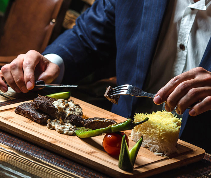 Artisinal steak with sauce and rice served on wooden board in restaurant
