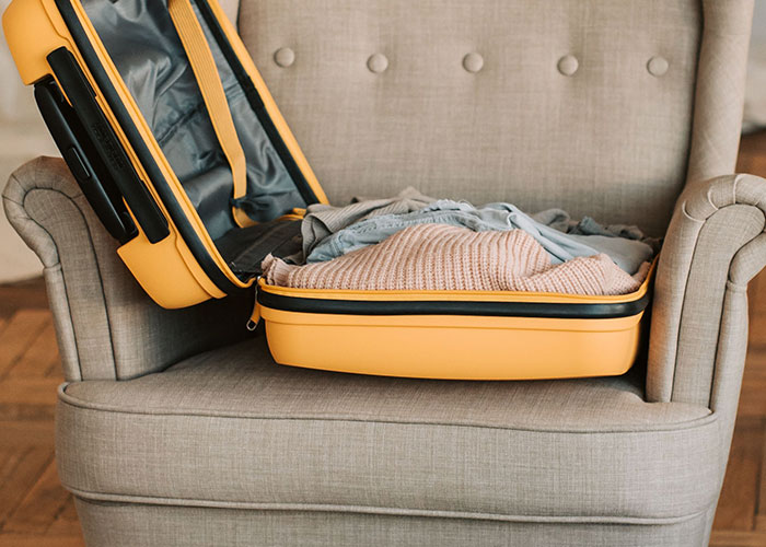 Open suitcase on armchair with clothes hinting at unexpected vanishing