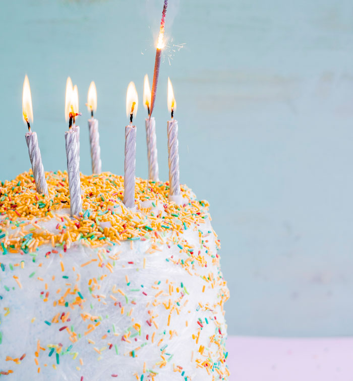 Birthday cake with lit candles and colorful sprinkles