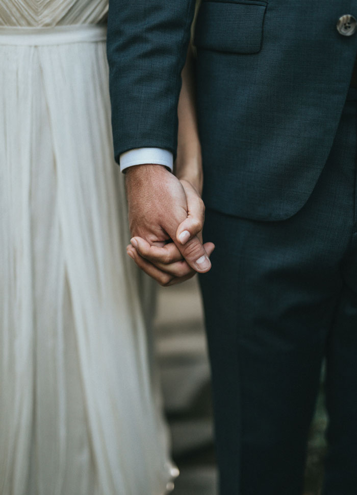 Close-up of bride and groom holding hands at wedding ceremony