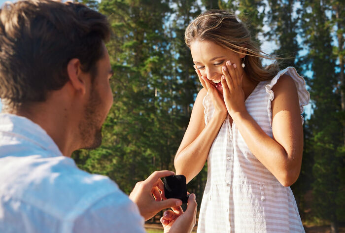 Man proposing to a surprised woman outdoors, symbolizing love, romance, and engagement stories.