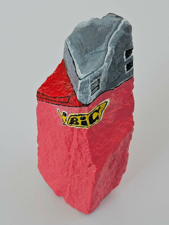A colorful stone creation shaped like a red Bic lighter with a gray top, turning rocks into famous products.