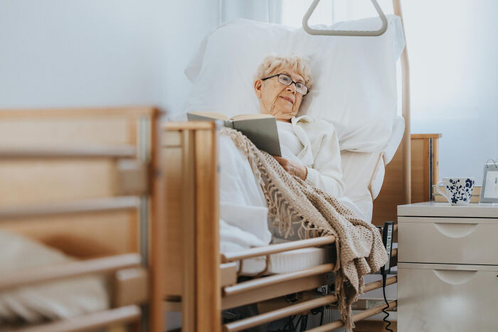 Elderly patient reading book in psychiatric facility bed