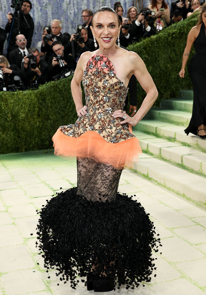 Woman in an elaborate, embellished dress with orange ruffles and a black feathered skirt, worst dressed at Met Gala.