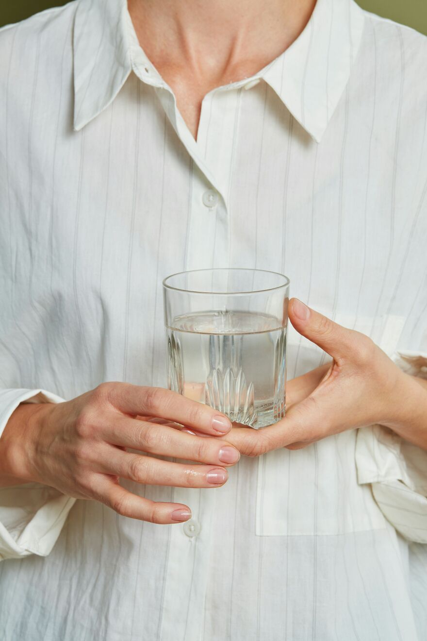 Woman in a white shirt holding a glass of water, highlighting everyday Japanese things and wellness.