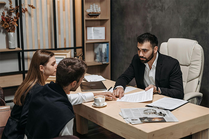 A lawyer explains a document to a couple, potentially related to adopting a grandchild or family legal matters.