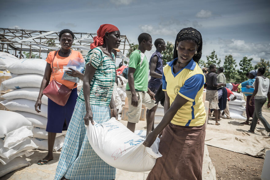 People carrying large bags, perhaps relief supplies, in a potentially stressful job environment outdoors.