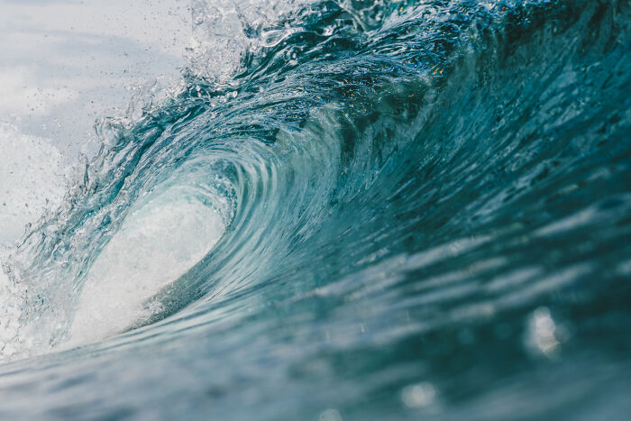 A powerful ocean wave curling, forming a blue barrel. People cross to the other side to experience such incredible sights.