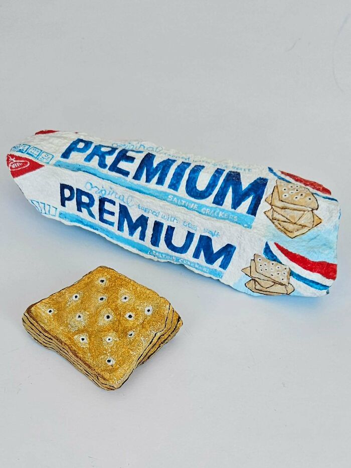 Colorful stone creations: A rock painted to resemble a pack of Premium saltine crackers and a single cracker rock.