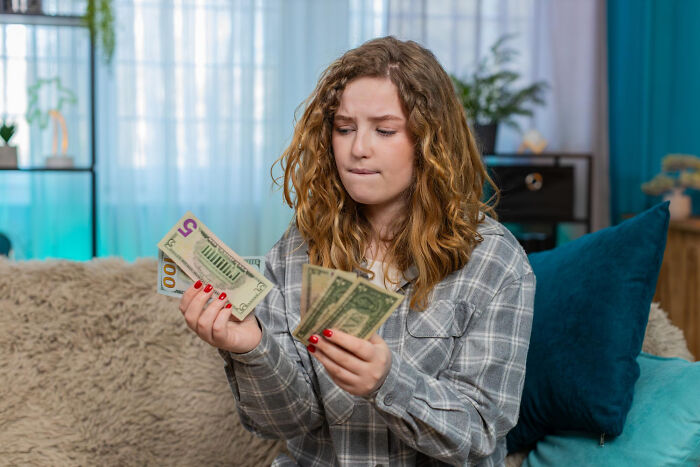 Worried woman counting money at home showing financial stress