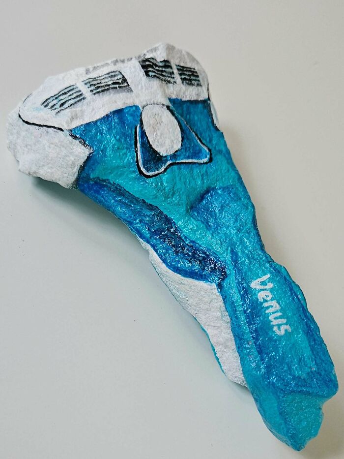 A rock painted to look like a blue and white Venus razor, an example of colorful stone creations as iconic products.