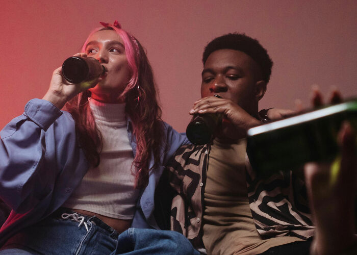 Two people drink from bottles, possibly concerning their wallets and the economy.