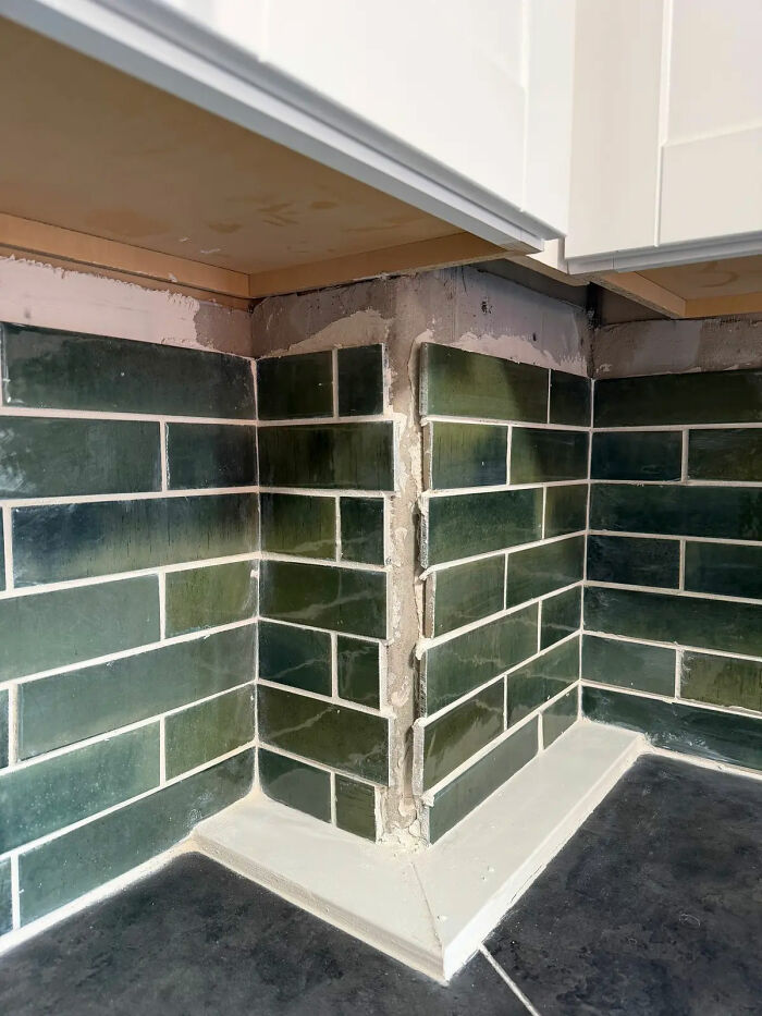 Poorly installed green subway tiles in a kitchen, showing gaps and uneven grout, a result of a bad contractor.