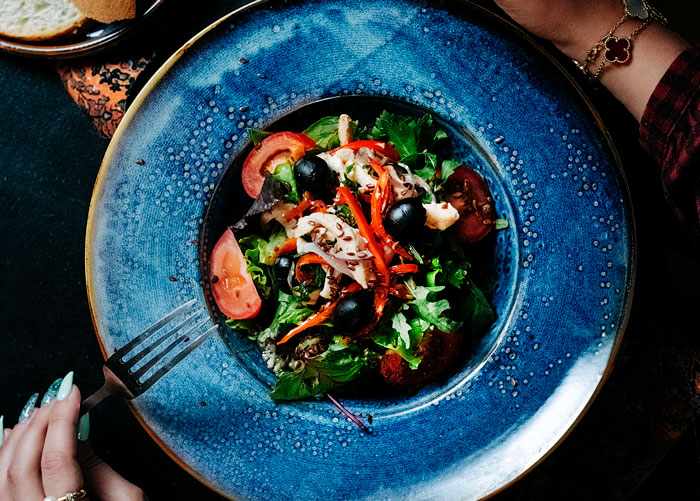 Fresh European salad with olives and vegetables on a blue plate