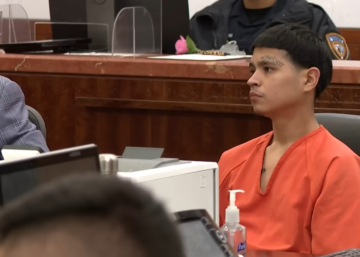Young man in orange prison uniform sitting in courtroom listening attentively Young man in orange prison uniform sitting in courtroom listening attentively
