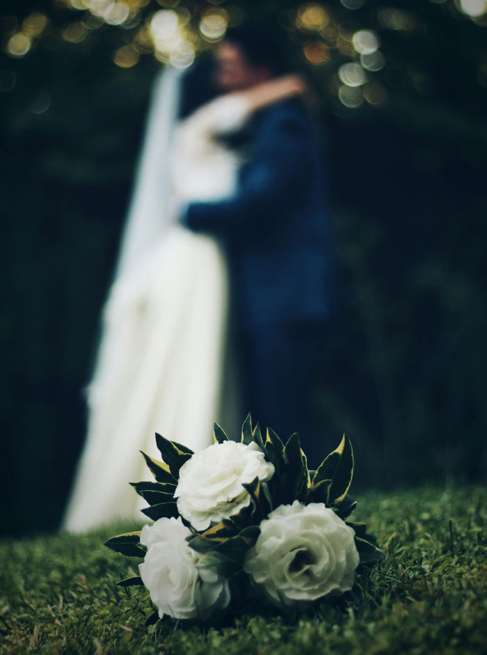 Wedding bouquet in focus with bride and groom blurred in background