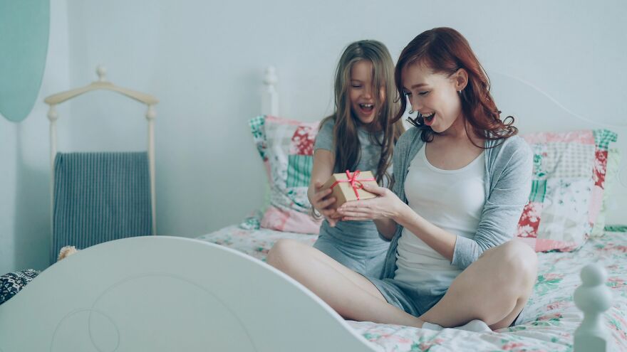 Mother and daughter smiling and exchanging gift capturing happy crying moment