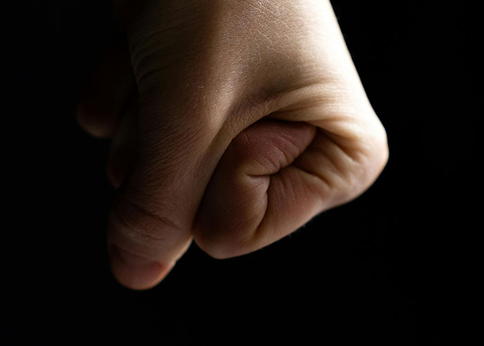 Close-up of a person's clenched fist in shadow, highlighting common stereotypes about the US that are untrue.