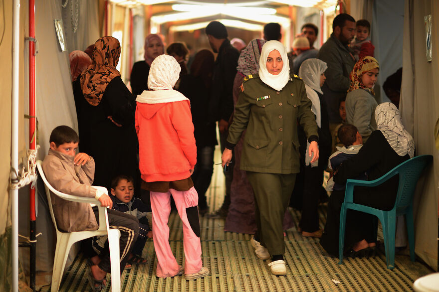 A female officer in uniform walks through a crowded hall of civilians. This represents one of the most stressful jobs.