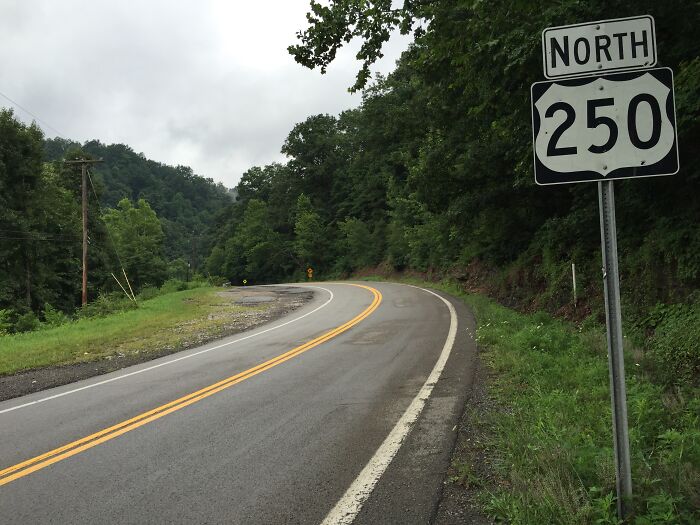 Curvy mountain highway on US Route 250 with dense trees along the roadside