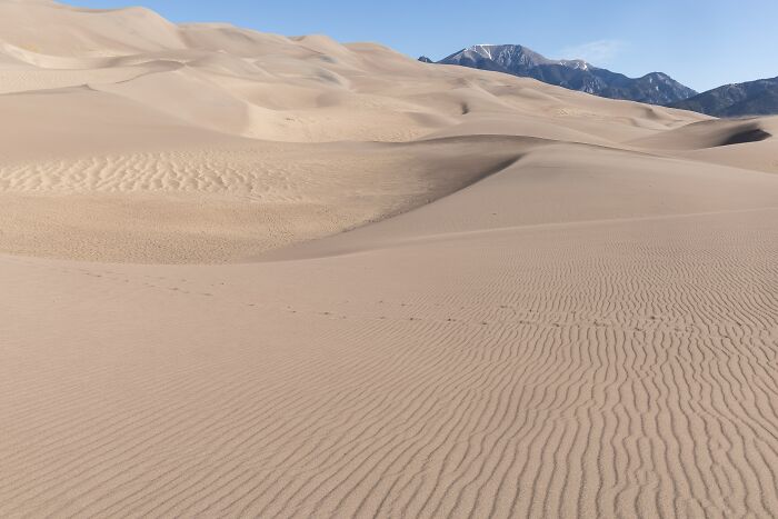 Vast sand dunes landscape with mountain backdrop stunning desert views