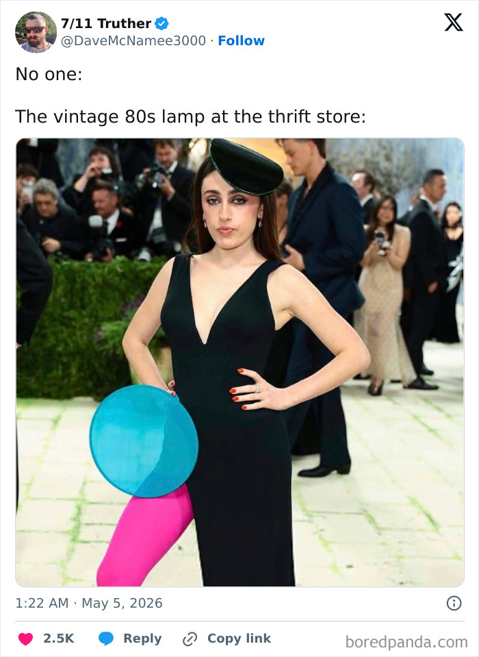 A woman in a black gown, a small hat, pink tights, and a blue disc, posing on a red carpet. MET Gala 2026 guest reactions.