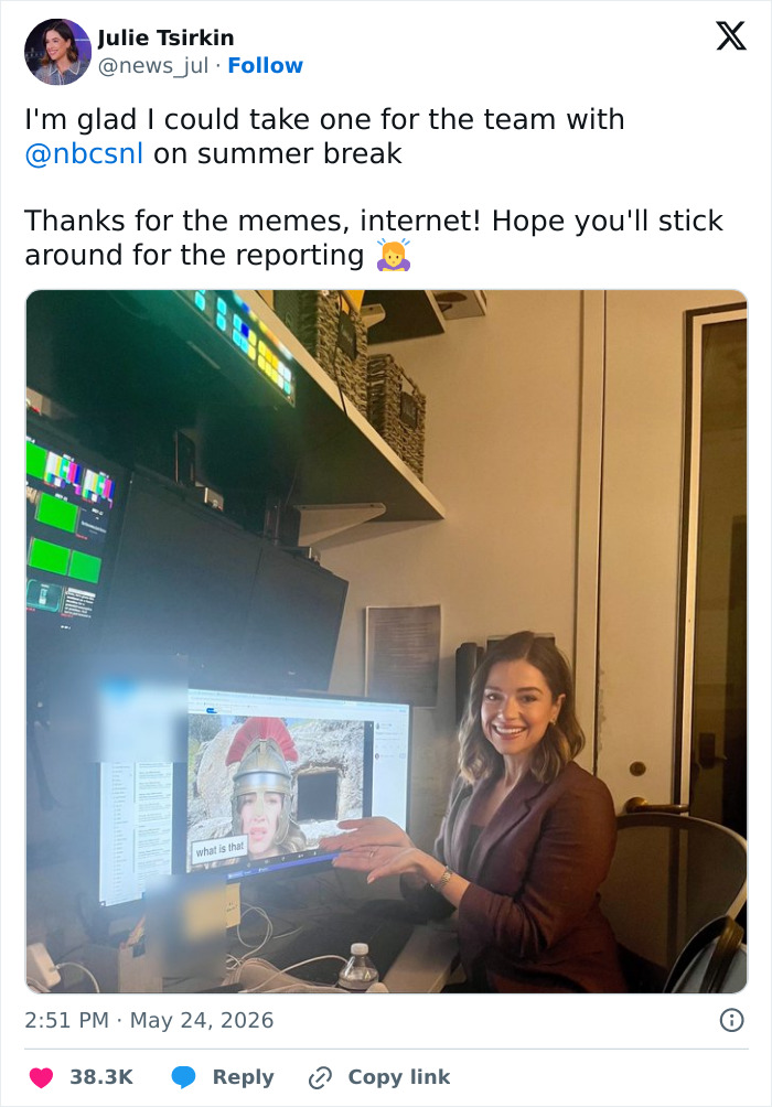 Reporter smiling and pointing to a meme on computer screen