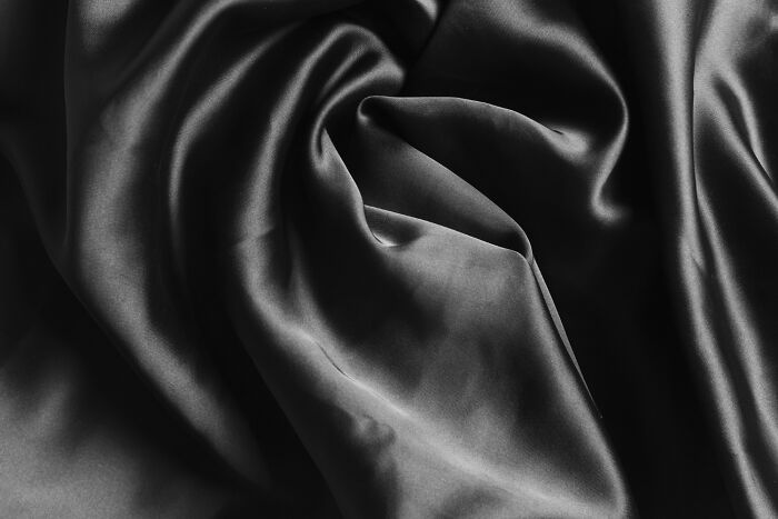 Smooth, dark gray fabric with soft folds and highlights, suggesting a mysterious journey, people cross to the other side.