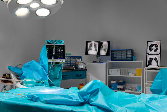 An operating room with a surgical light, medical equipment, and chest X-rays. Many people who cross to the other side have stories.