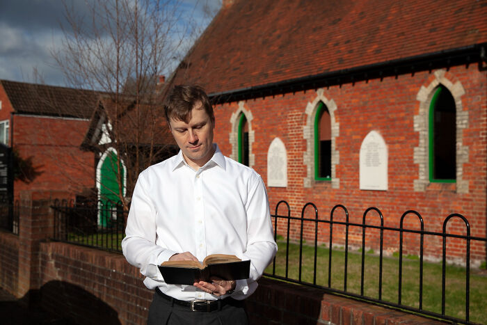 Man reading a book outdoors in front of a brick building for conspiracy theory moments explained by facts