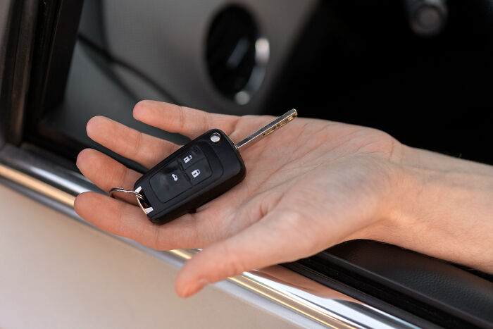 Hand holding car key while sitting in vehicle showing car key fob