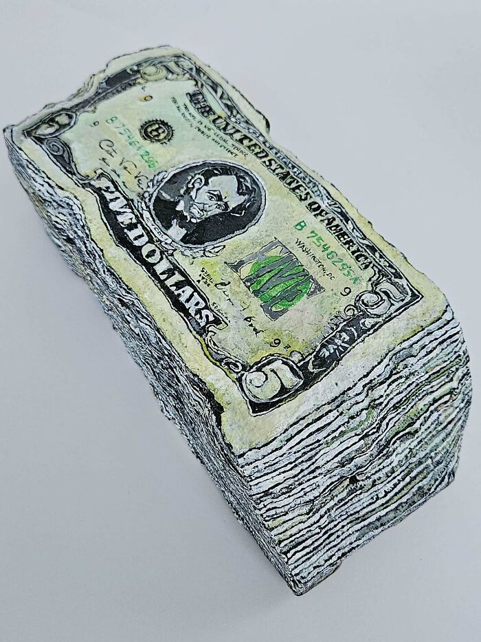 A stack of five-dollar bills made from colorful stone creations, turning rocks into iconic foods and famous products.