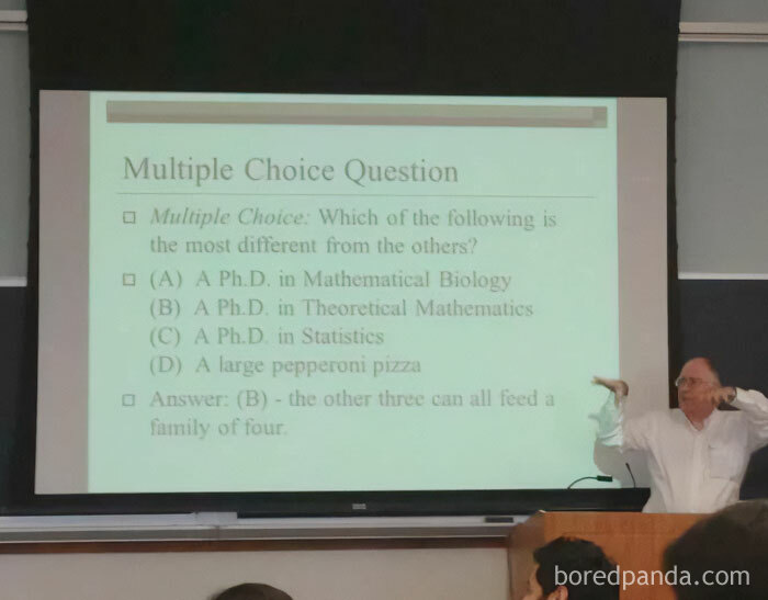 A math professor gestures during a lecture, showing a funny multiple-choice question on a screen. Math memes.
