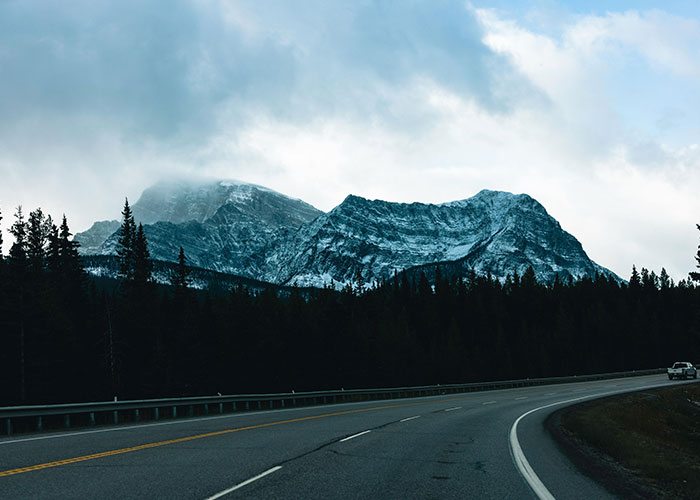 Deserted highway near dark mountains under cloudy sky hinting at mysterious disappearances