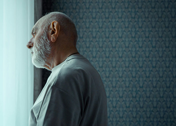 Elderly man staring out window, conveying themes of people mysteriously vanishing