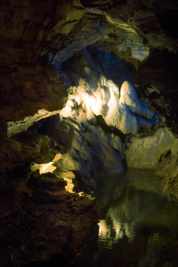 Illuminated cave interior with rocky formations and reflective water
