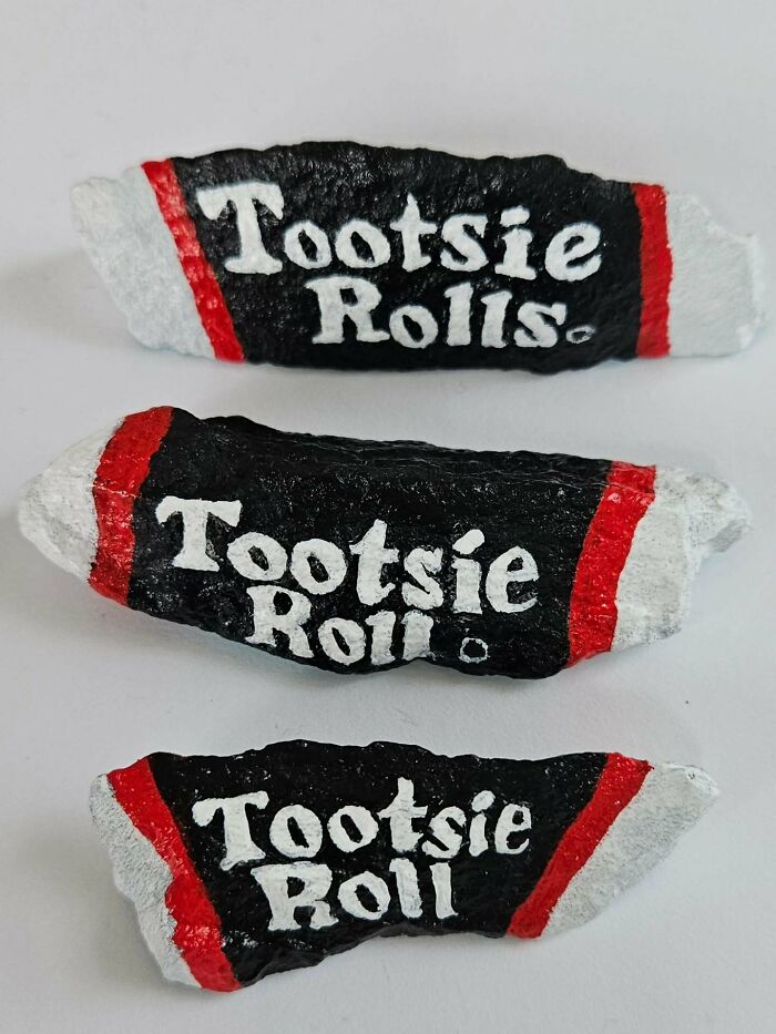 Three painted rocks designed as Tootsie Roll candies. This is an example of colorful stone creations as iconic foods.