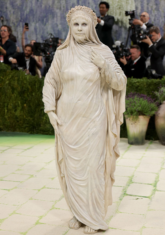 A person in a flowing, statue-like white gown and veiled face, among the worst dressed stars at Met Gala 2026.